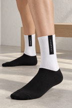 Close-up of CRAMPFIT crew socks showing white ribbed knit and the vertical black brand panel.