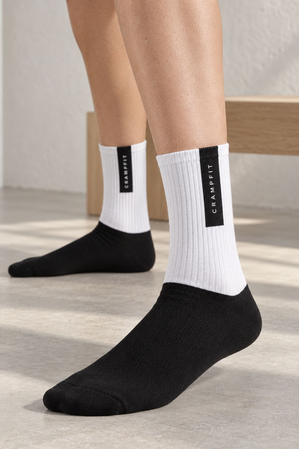 Close-up of CRAMPFIT crew socks showing white ribbed knit and the vertical black brand panel.