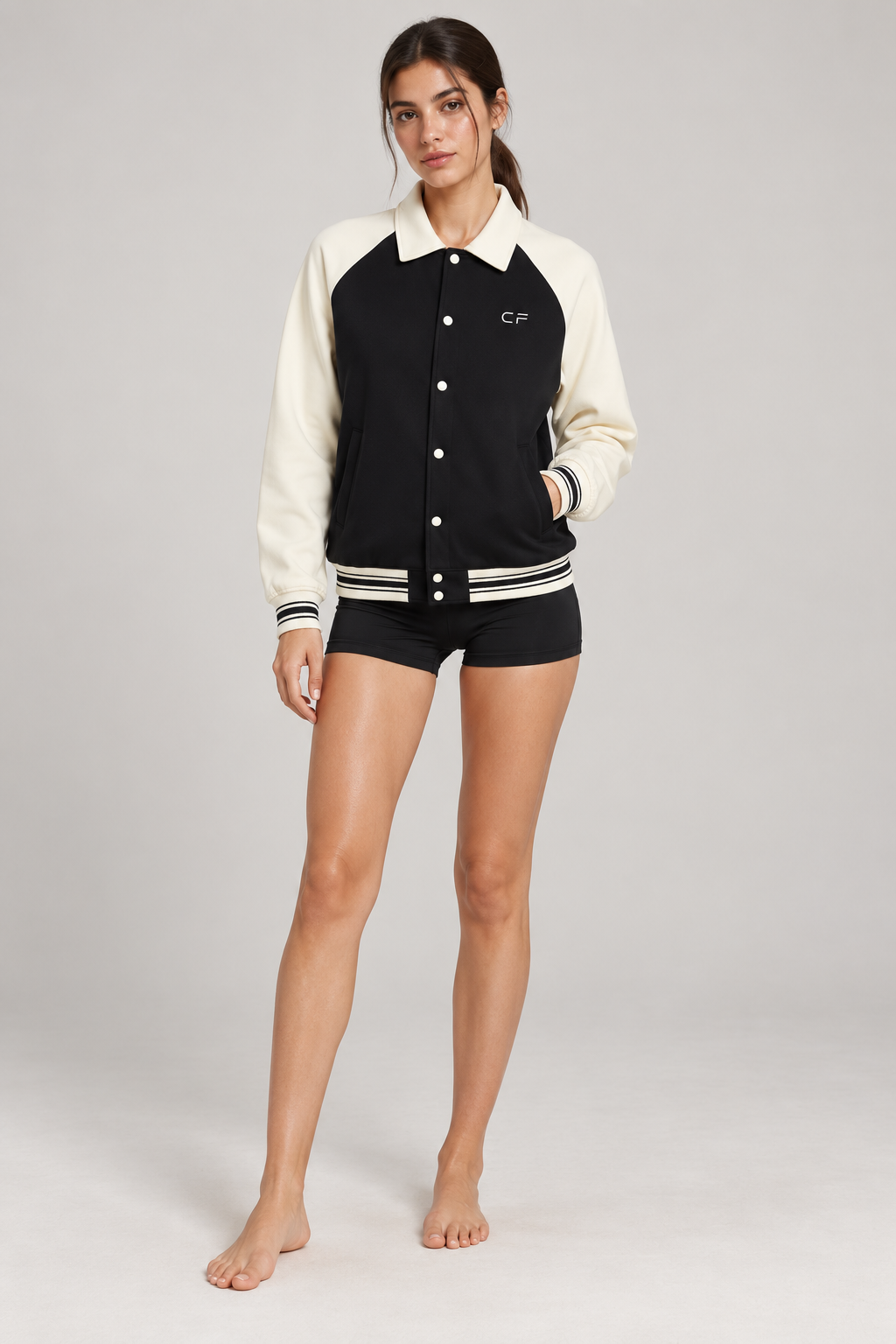 CRAMPFIT Raglan Varsity Jacket in black and cream, front view on a slim female model
