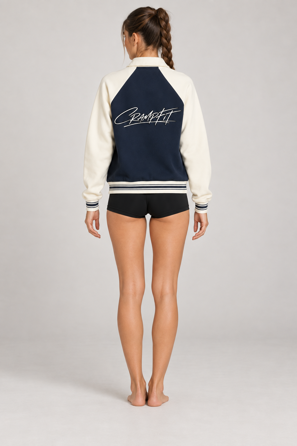 CRAMPFIT Raglan Varsity Jacket in navy and cream, back logo view on a slim female model