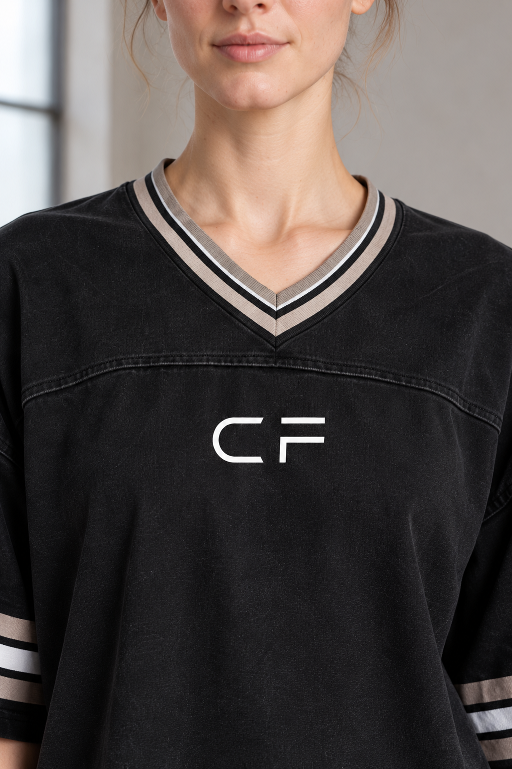 Close-up of CRAMPFIT black boxy jersey showing striped V-neck, chest seam and CF logo.