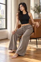 Model seated in CRAMPFIT espresso wide-leg cotton sweatpants in natural window light.