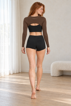 CRAMPFIT brown cutout shrug, rear view showing the curved back hem and CRAMPFIT branding. Styled over a separate black sports bra.