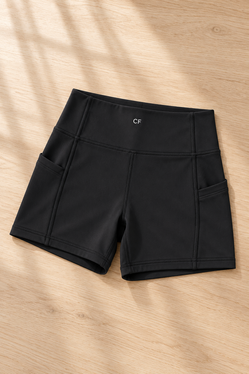 CRAMPFIT women's high-rise pocket yoga shorts in black, flat-lay detail of the waistband, side pockets and stitching.