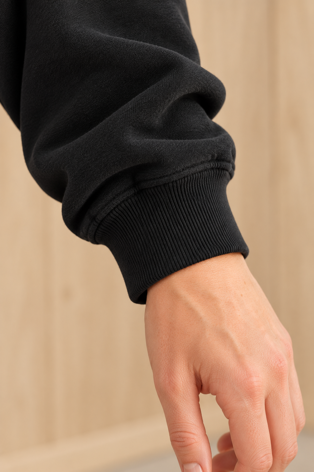 Close-up of CRAMPFIT black mockneck sweatshirt showing ribbed sleeve cuff, stitching and fabric texture.