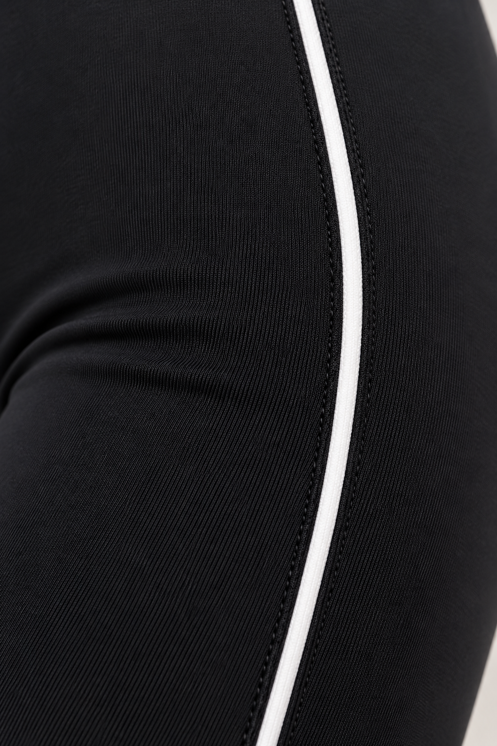 Close-up of CRAMPFIT black Sculpt Legging showing white contour piping, stitching and stretch fabric texture.