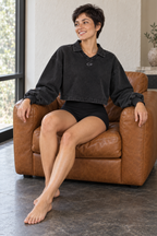 CRAMPFIT women's vintage wash crop sweatshirt in black, editorial view seated in a leather armchair.