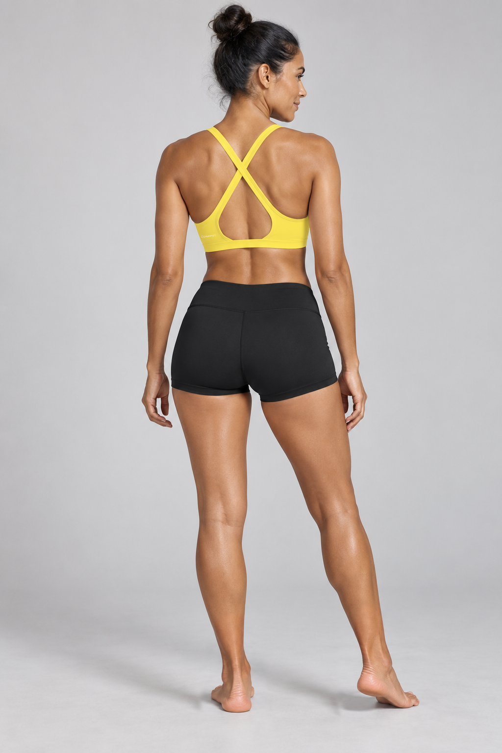 CRAMPFIT Women's Yoga Sports Bra - yellow back view, barefoot, styled with black workout shorts